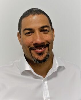 Daniel Robinson, olive skin, dark hair and short manicured beard wearing white shirt