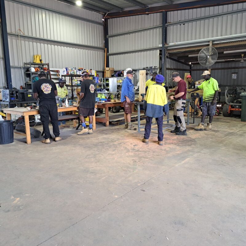 A group of First Nations men in a tin shed working on different pieces of word to hone their carpentry skills
